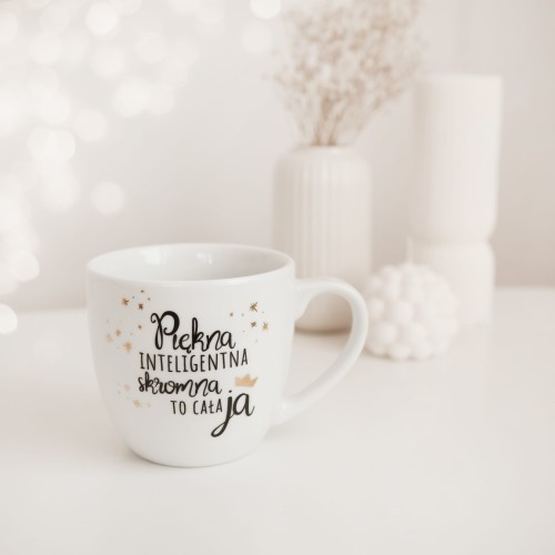 Biały kubek porcelanowy Nadzwyczajnie.pl ze złotym zdobieniem i napisem Piękna, inteligentna, skromna to cała ja — 300 ml
