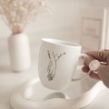 Biały Kubek Porcelanowy z Personalizacją 380 ml - Splecione Dłonie z Imionami i Serduszkami dla Pary na Każdą Okazję Kubek porcelanowy ze złotym zdobieniem Biały Kubek Porcelanowy z Personalizacją 380 ml - Splecione Dłonie z Imionami i