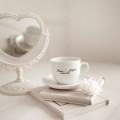 Biała Filiżanka Porcelanowa ze Spodkiem 200 ml - Personalizacja Imion i Daty ze Złotym Sercem dla Pary na Każdą Okazję Biały filiżanka porcelanowa Nadzwyczajnie.pl ze złotym zdobieniem i napisem Biała Filiżanka Porcelanowa ze Spodkiem 200
