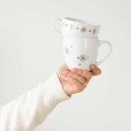 Kubek 300 ml - Złote stokrotki Zbliżenie na złote zdobienie na białym kubku porcelanowym Złote stokrotki Nadzwyczajnie.pl