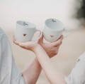 Zestaw 2 Białych Kubków Porcelanowych 300 ml - Napis Mąż i Żona oraz Złote Serce na Rocznicę Ślubu dla Pary Zbliżenie na złote zdobienie serca na białym zestawie porcelanowym 2 Białych Kubków Porcelanowych 300 ml - Napis Mąż i