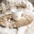 Biały kubek porcelanowy 300 ml - napis słuchaj ciszy ze złotym sercem dla mamy na Dzień Matki Zbliżenie na złote zdobienie serca na białym kubku porcelanowym Słuchaj ciszy Nadzwyczajnie.pl