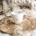 Biały kubek porcelanowy 300 ml - napis bądź tu i teraz ze złotym sercem dla miłośników uważności na urodziny Zbliżenie na złote zdobienie serca na białym kubku porcelanowym bądź tu i teraz Nadzwyczajnie.pl